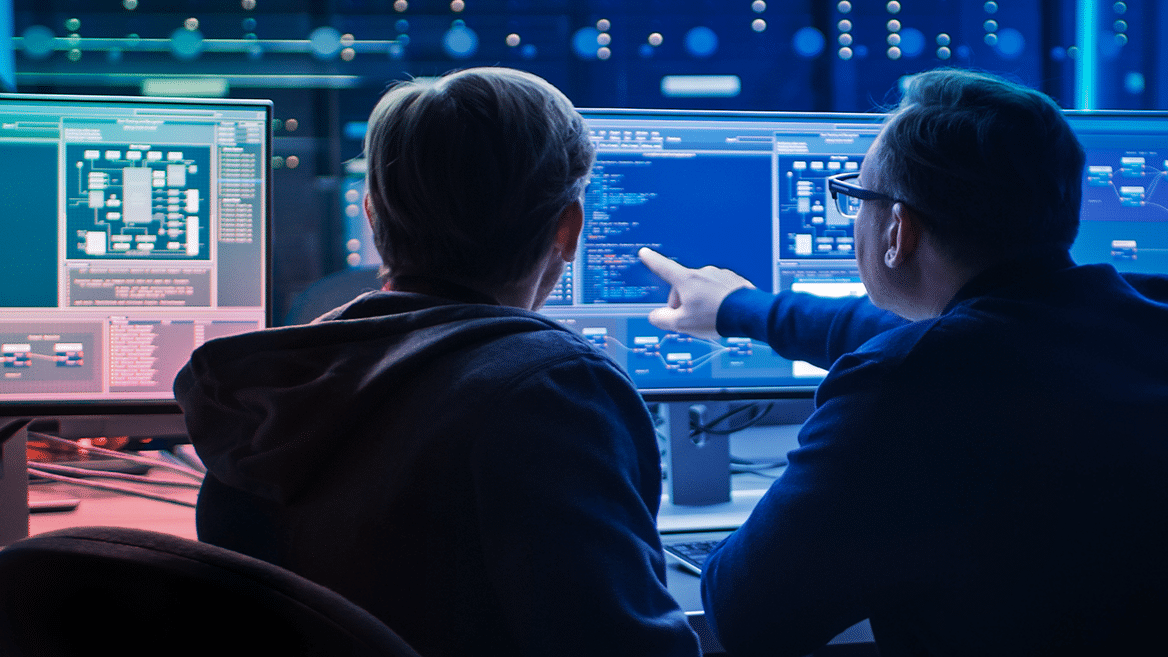 2 personnes devant des écrans pleins de codes