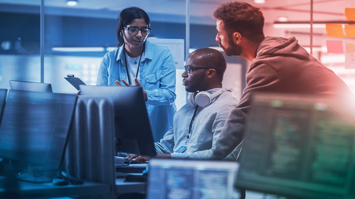 3 personnes discutant devant des écrans